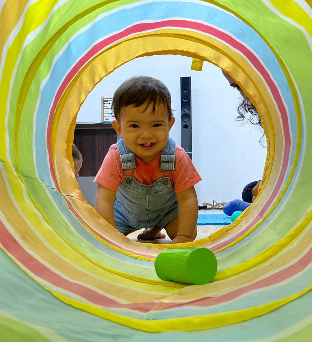 Bebé gateando dentro de un túnel de juegos.”